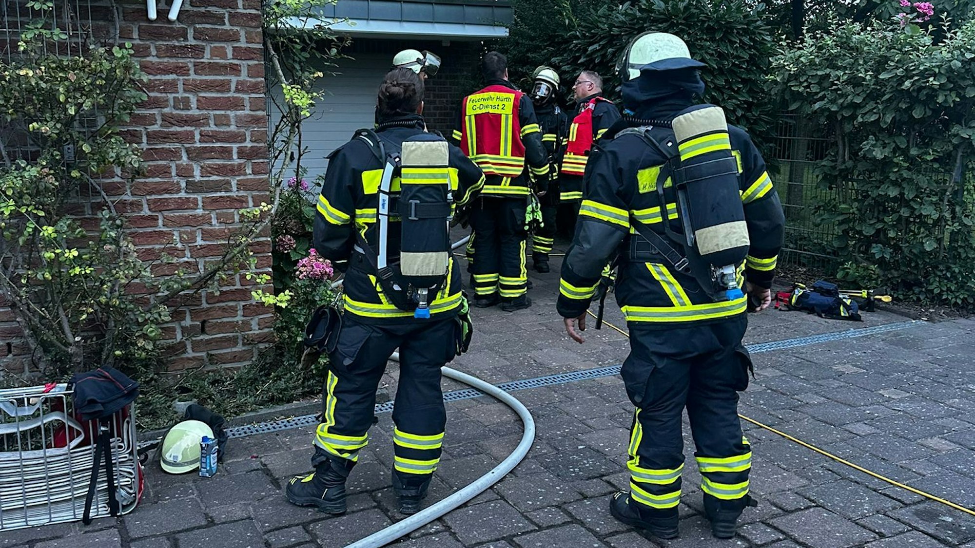 Feuerwehrleute stehen vor einer Garage.