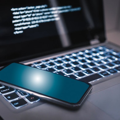 Ein Handy liegt auf der Tastatur eines Laptops.