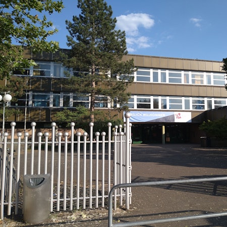 Zu sehen ist das Heinrich-Mann-Gymnasiums in Chorweiler von außen.