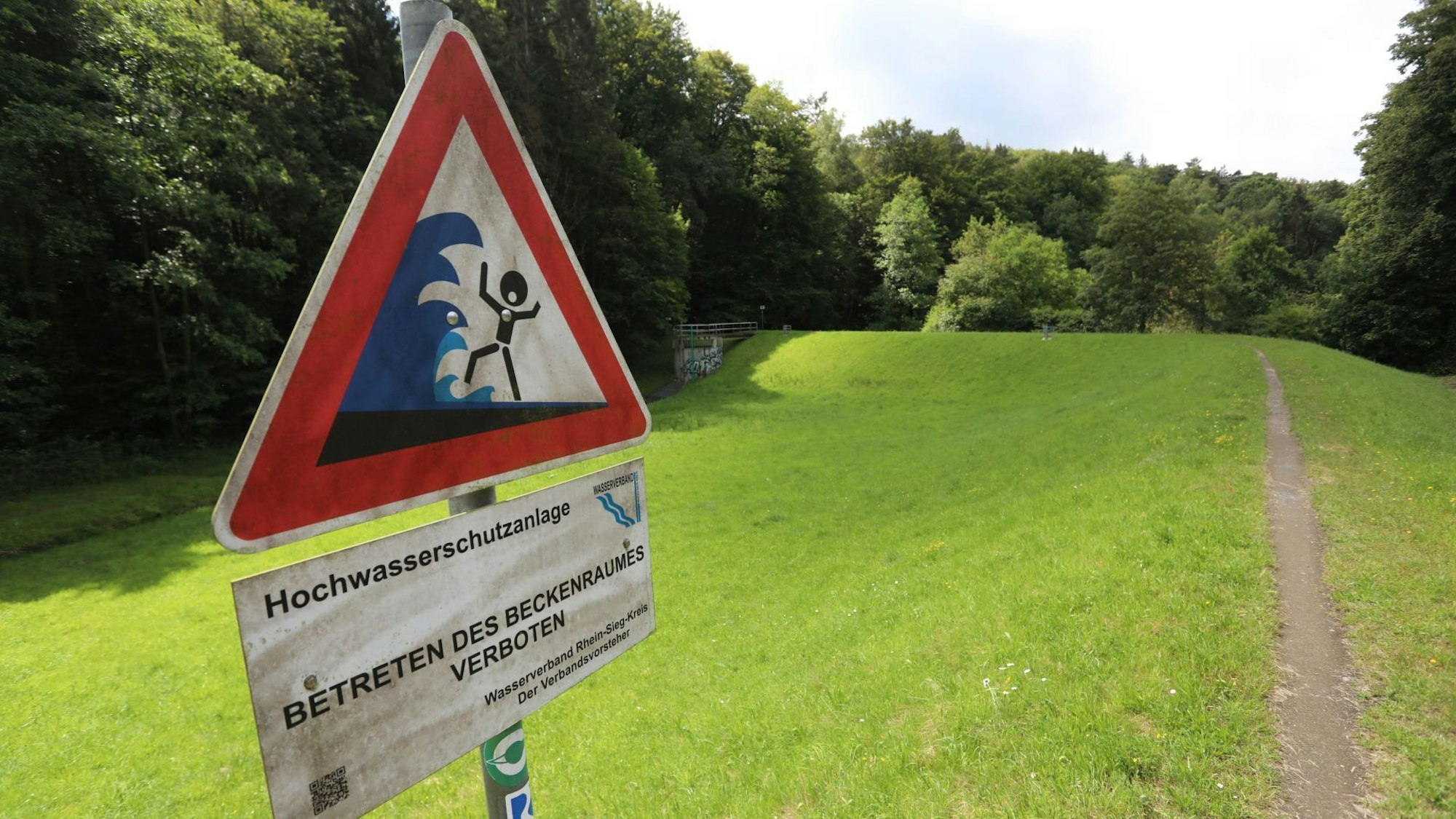 Ein Warnschild vor Hochwasser am Rande des Hochwasserrückhaltebeckens.