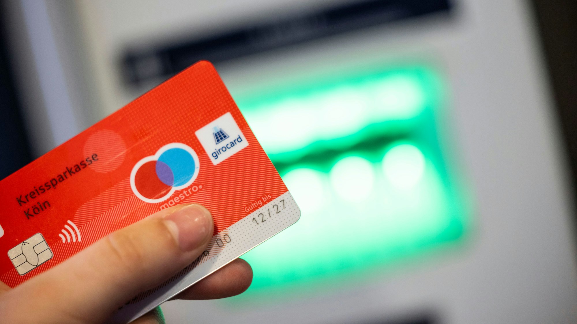 Eine Bankkundin verwendet ihre Girokarte, um Bargeld an einem Geldautomaten abzuheben.