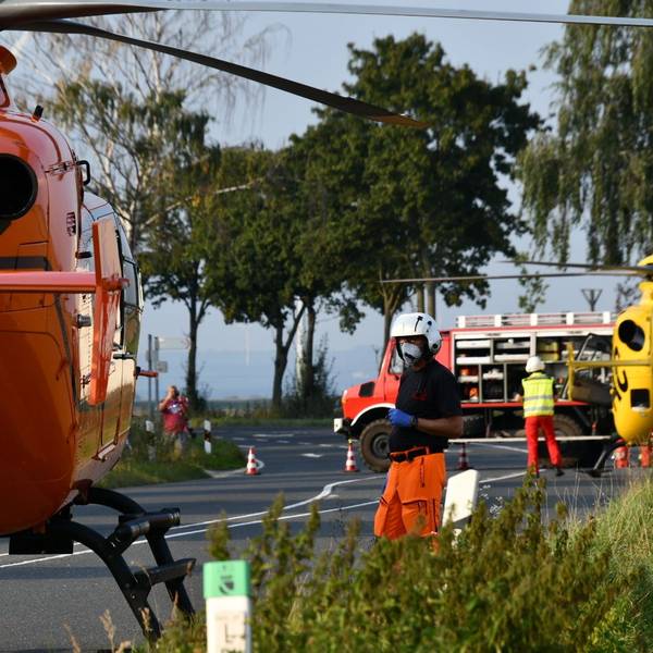 Einsatzkräfte stehen neben einem Rettungshubschrauber auf einer Landstraße (Symbolfoto).