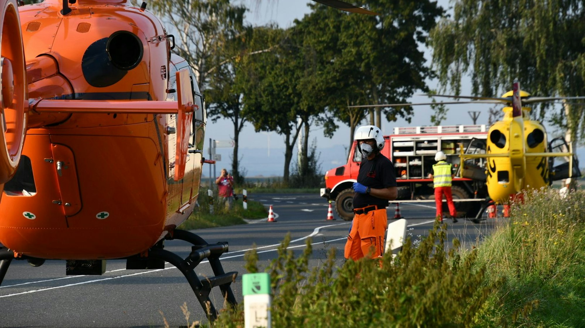 Einsatzkräfte stehen neben Rettungshubschraubern auf einer Landstraße (Symbolfoto).