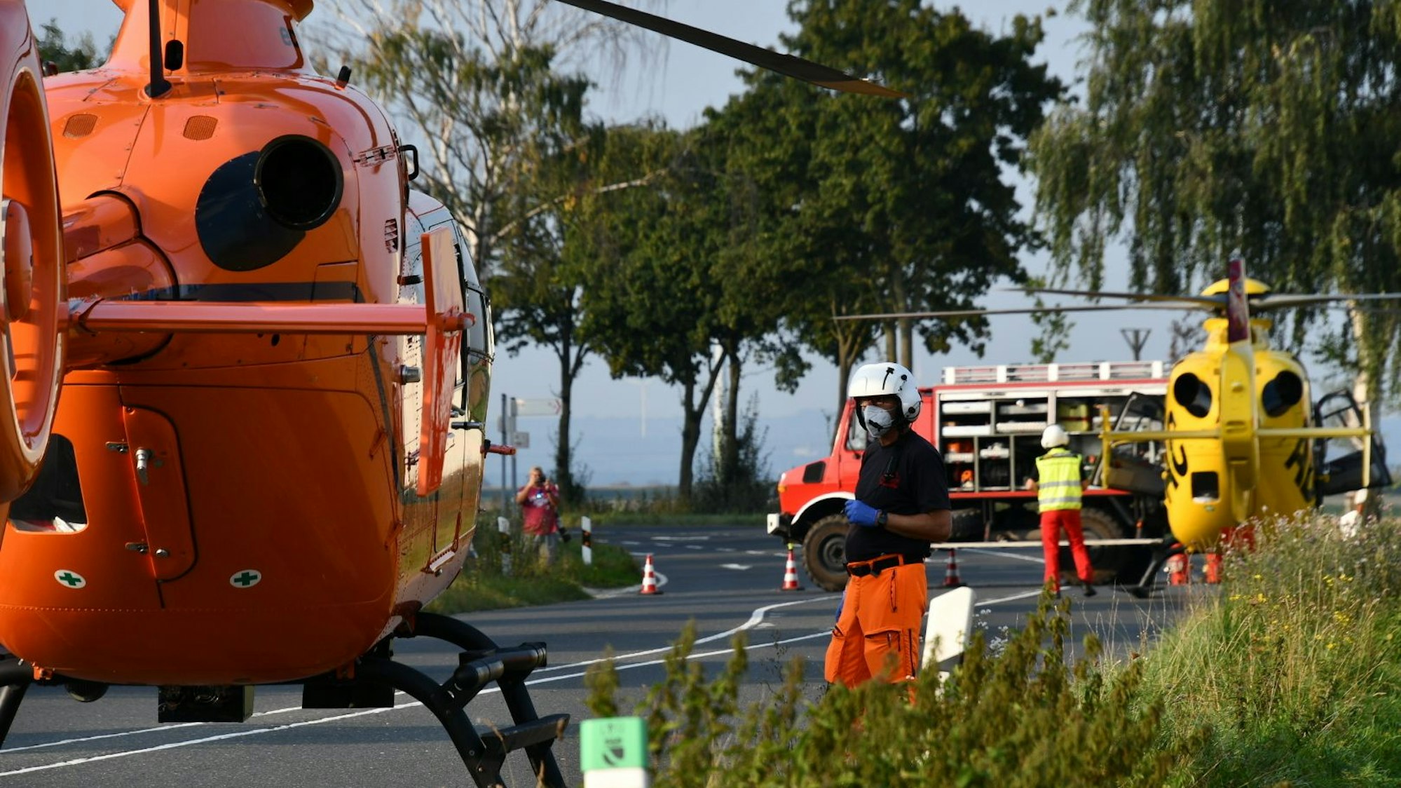 Einsatzkräfte stehen neben einem Rettungshubschrauber auf einer Landstraße (Symbolfoto).