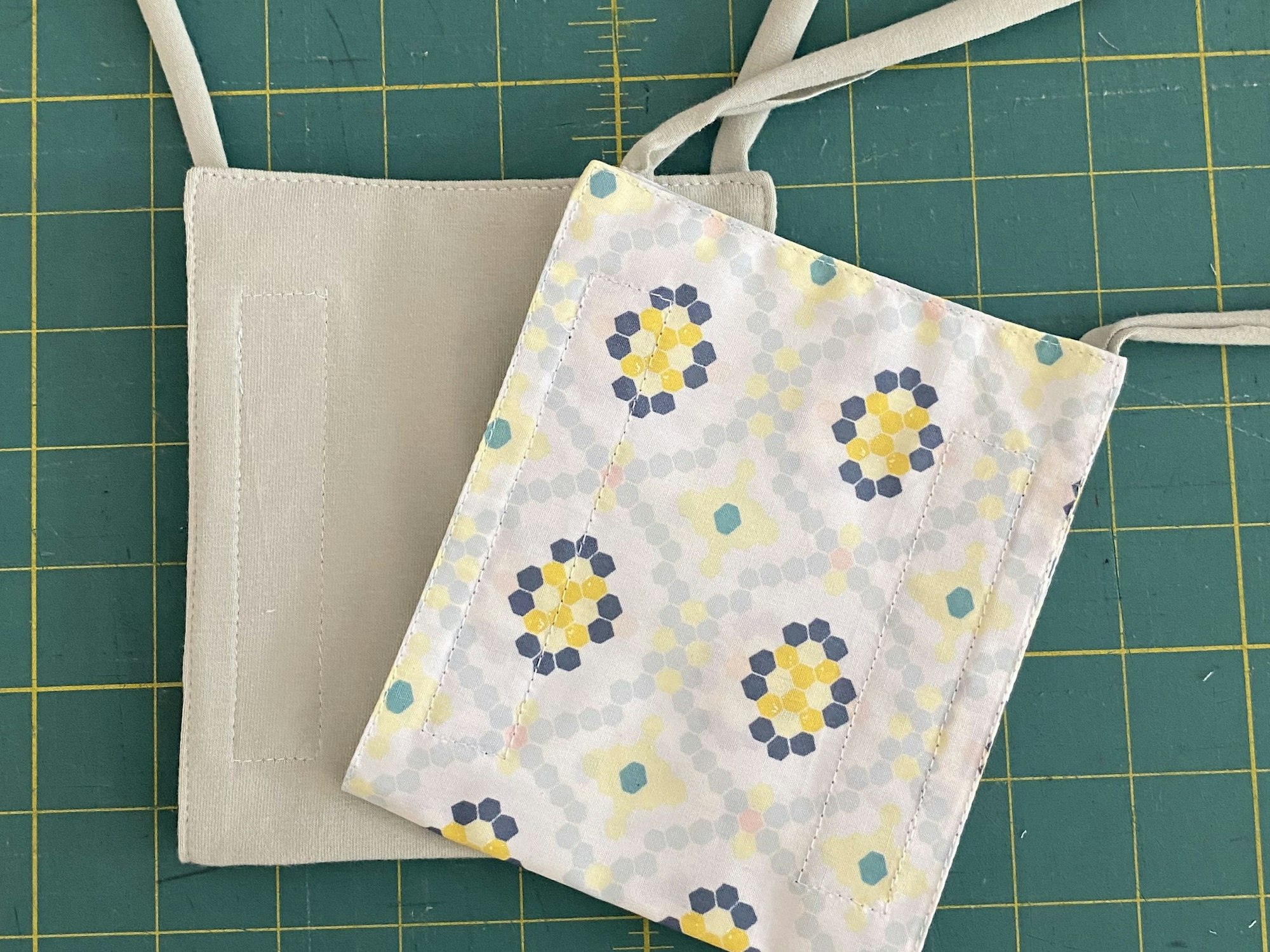 Auf einem grünen Tisch mit einem gelben Karo-Muster liegen zwei kleine Umhängetaschen.