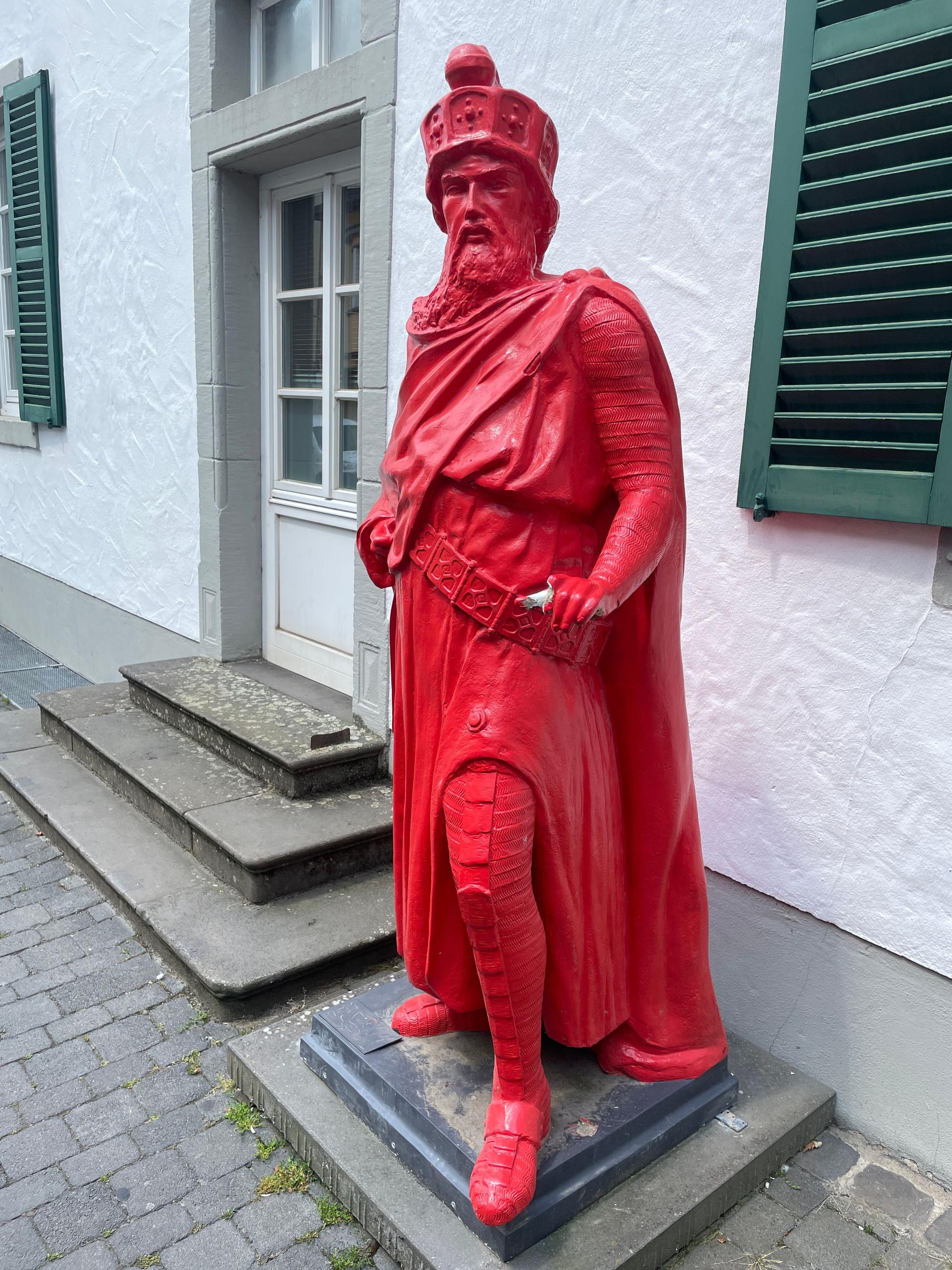 Eine Barbarossa-Statue ganz in Rot steht vor einem Haus.