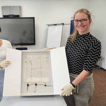 Eine Urkunde aus Schleiden aus dem Jahr 1521 präsentieren Lara Vogelsberg (l.) und Nicole Gutmann in einem Karton.