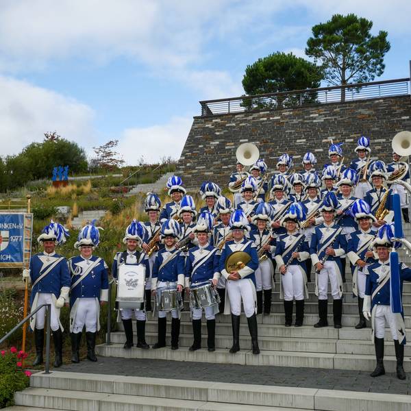 Das Bild zeigt den Musikzug der Blauen Funken auf dem Gelände des Seeparks in Zülpich. Sie stehen auf einer Treppe.