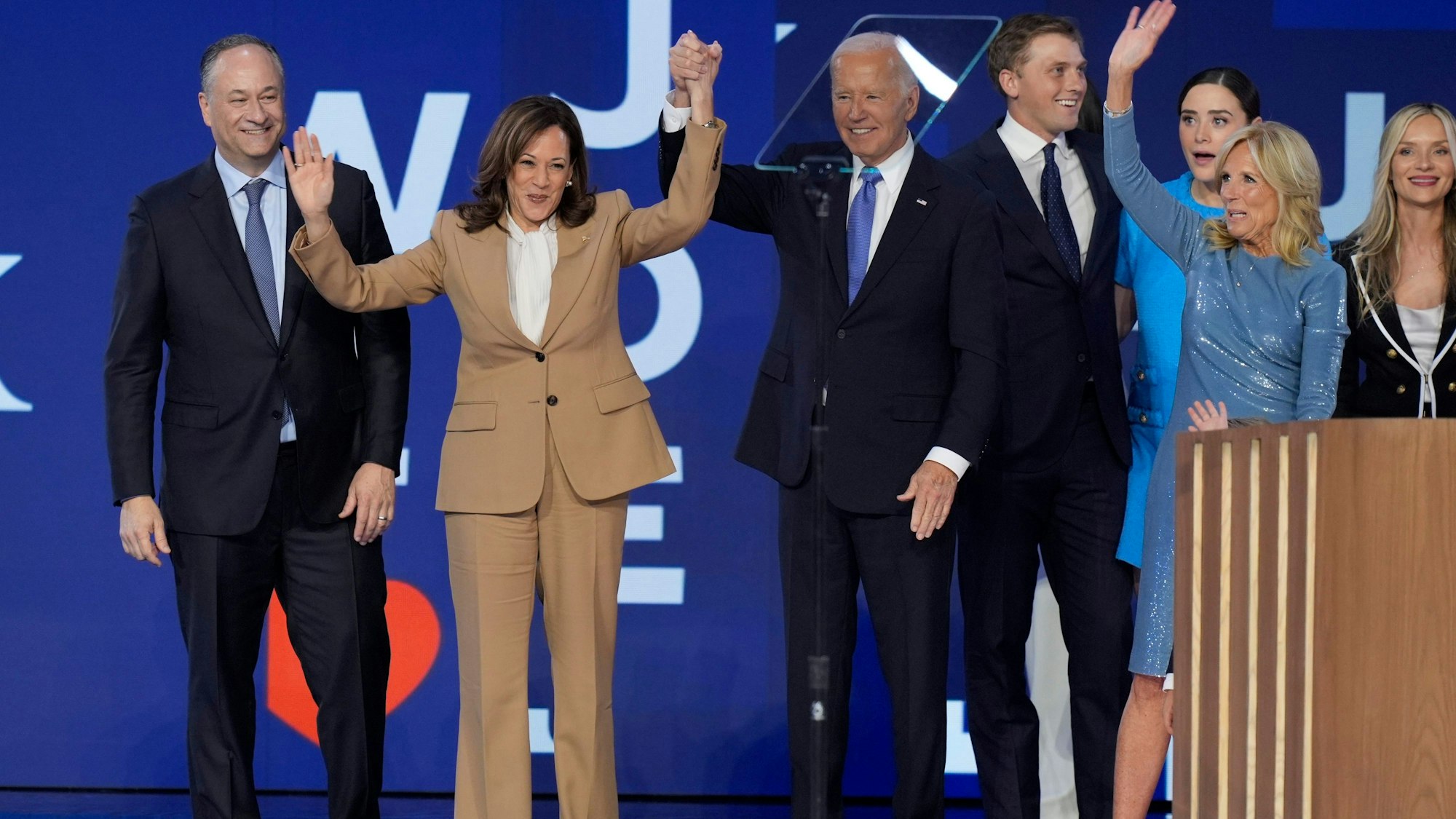 19.08.2024, USA, Chicago: US-Präsident Joe Biden hält einen Arm der demokratischen US-Präsidentschaftskandidatin Kamala Harris hoch, zwischen Harris Mann, Second Gentleman Doug Emhoff (l) und der First Lady der USA, Jill Biden (r), auf der Bühne.