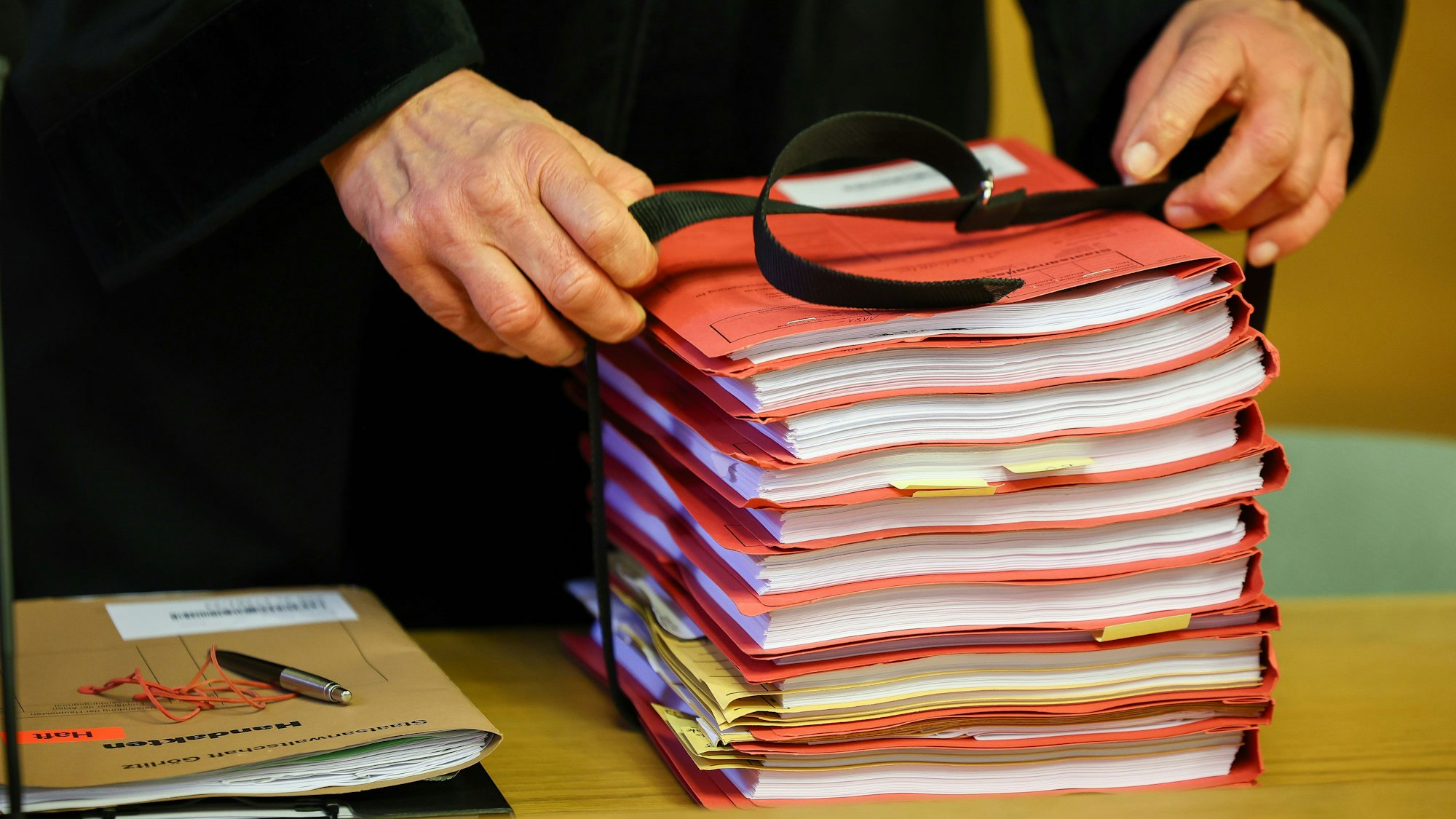 Ein Staatsanwalt legt einen Stapel Akten vor Prozessbeginn auf seinen Tisch im Landgericht.