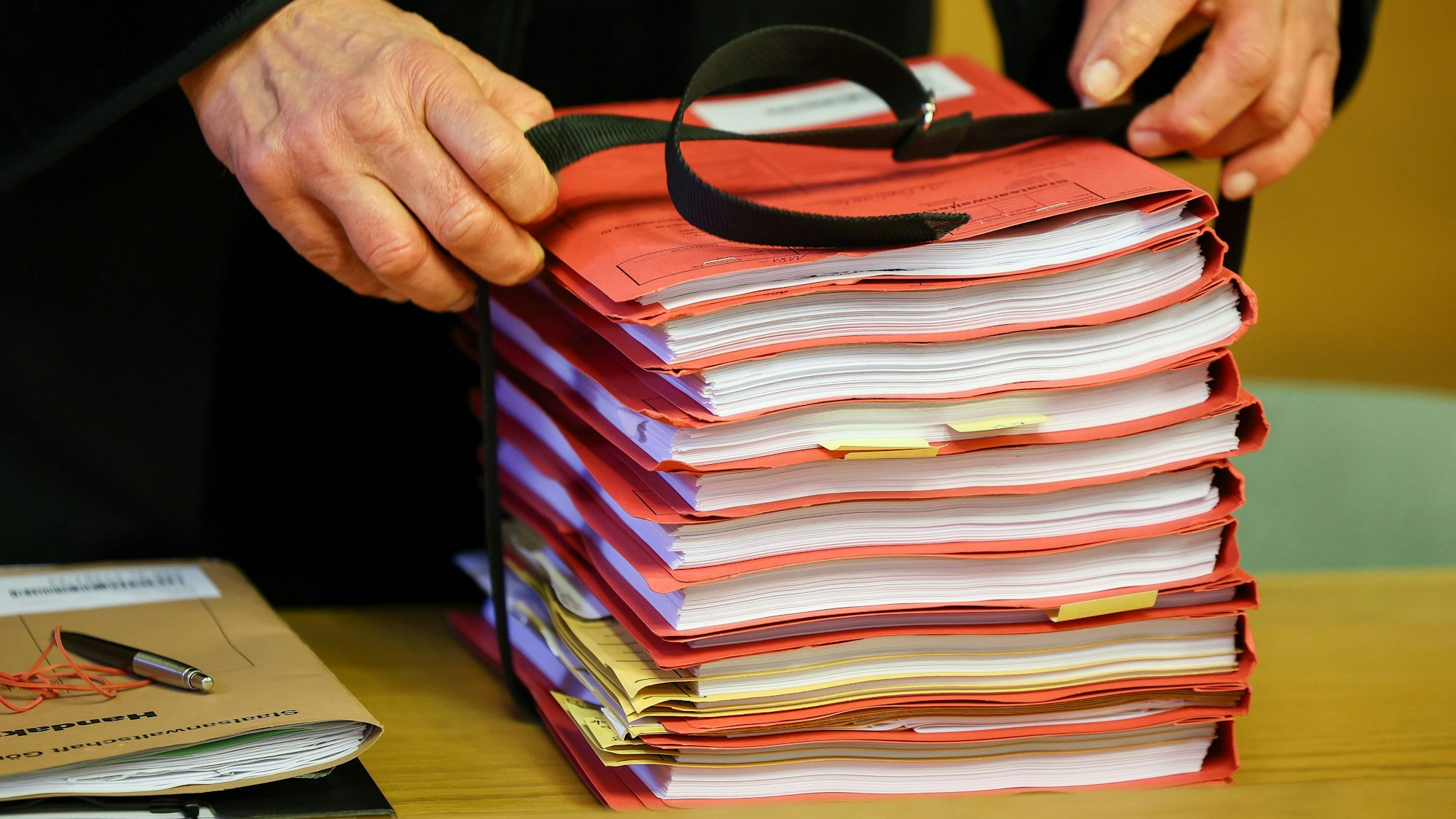 Der Staatsanwalt legt einen Stapel Akten auf seinen Tisch.