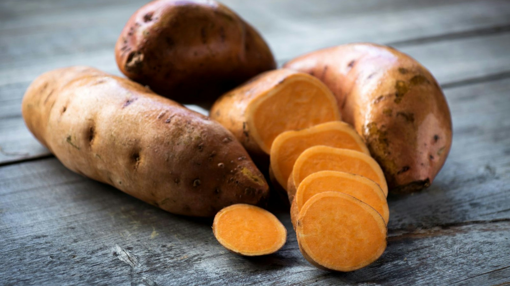 Aufgeschnittene Süßkartoffeln liegen auf einem Tisch.