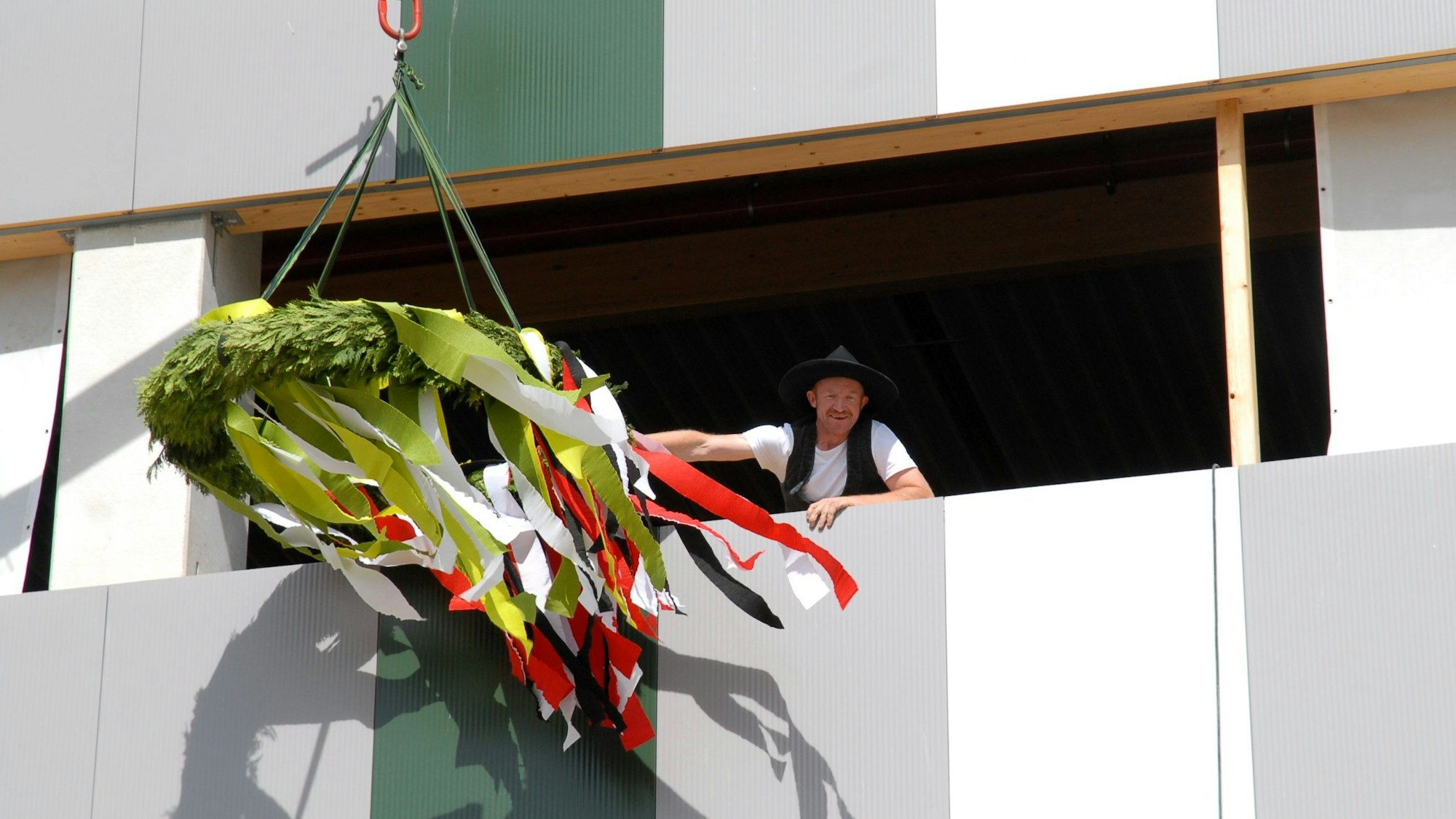 Ein Zimmermann schwenkt einen Richtkranz.