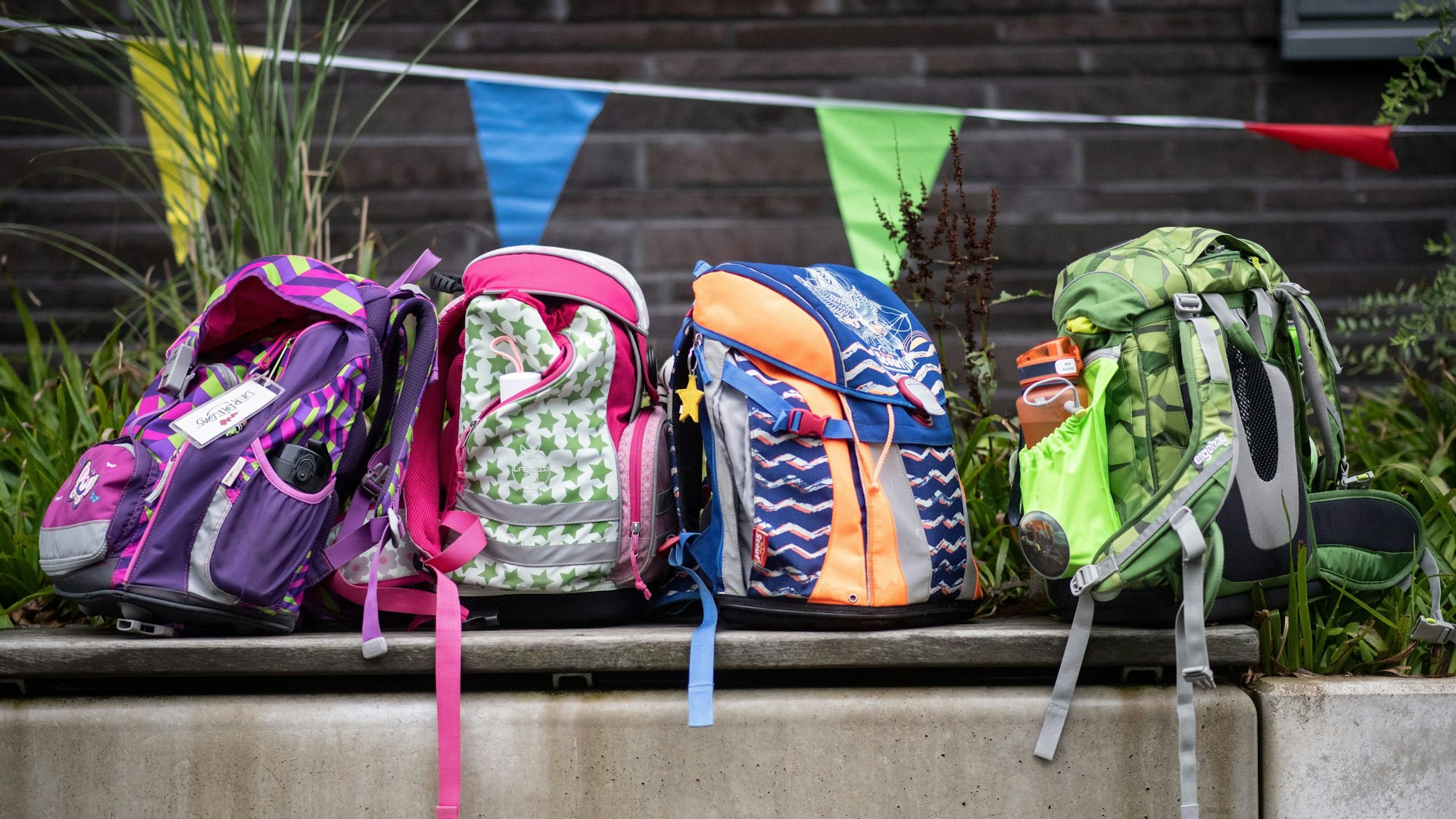 ARCHIV - 18.08.2021, Nordrhein-Westfalen, Wuppertal: Vier Schulranzen stehen bei der Einschulung auf einer Bank. Nach sechseinhalb Wochen Sommerferien beginnt für die meisten der gut 2,5 Millionen Schülerinnen und Schüler am Mittwoch in Nordrhein-Westfalen wieder der Unterricht. (zu dpa: «Rund 2,5 Millionen Schüler starten ins neue Schuljahr») Foto: Bernd Thissen/dpa +++ dpa-Bildfunk +++