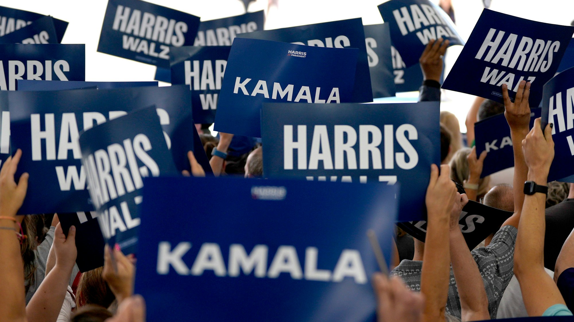 Unterstützer halten Schilder, bevor die demokratische Präsidentschaftskandidatin Kamala Harris auf dem internationalen Flughafen von Pittsburgh eintrifft.