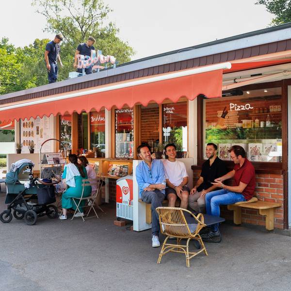 Das Büdchen am Südpark, davor sitzen einige Leute auf Bänken.
