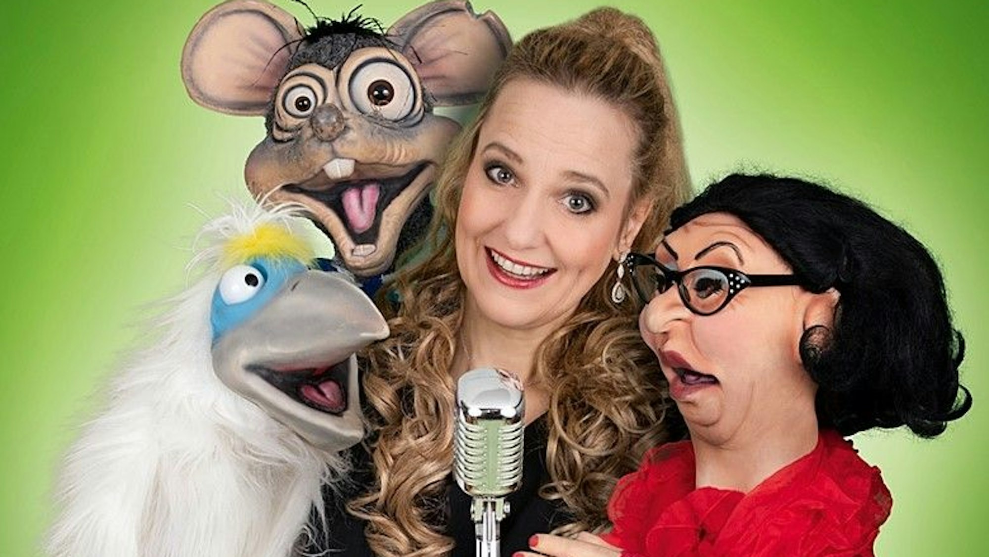 Eine Frau steht mit Puppen vor einem Mikrofon.