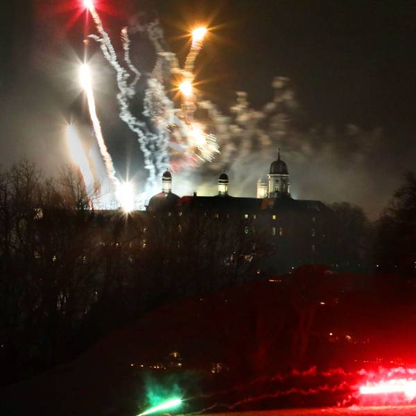 Im Vordergrund sieht man im Dunkeln die Umrisse vom Schloss Bensberg. Im Hintergrund Silvester-Raketen.