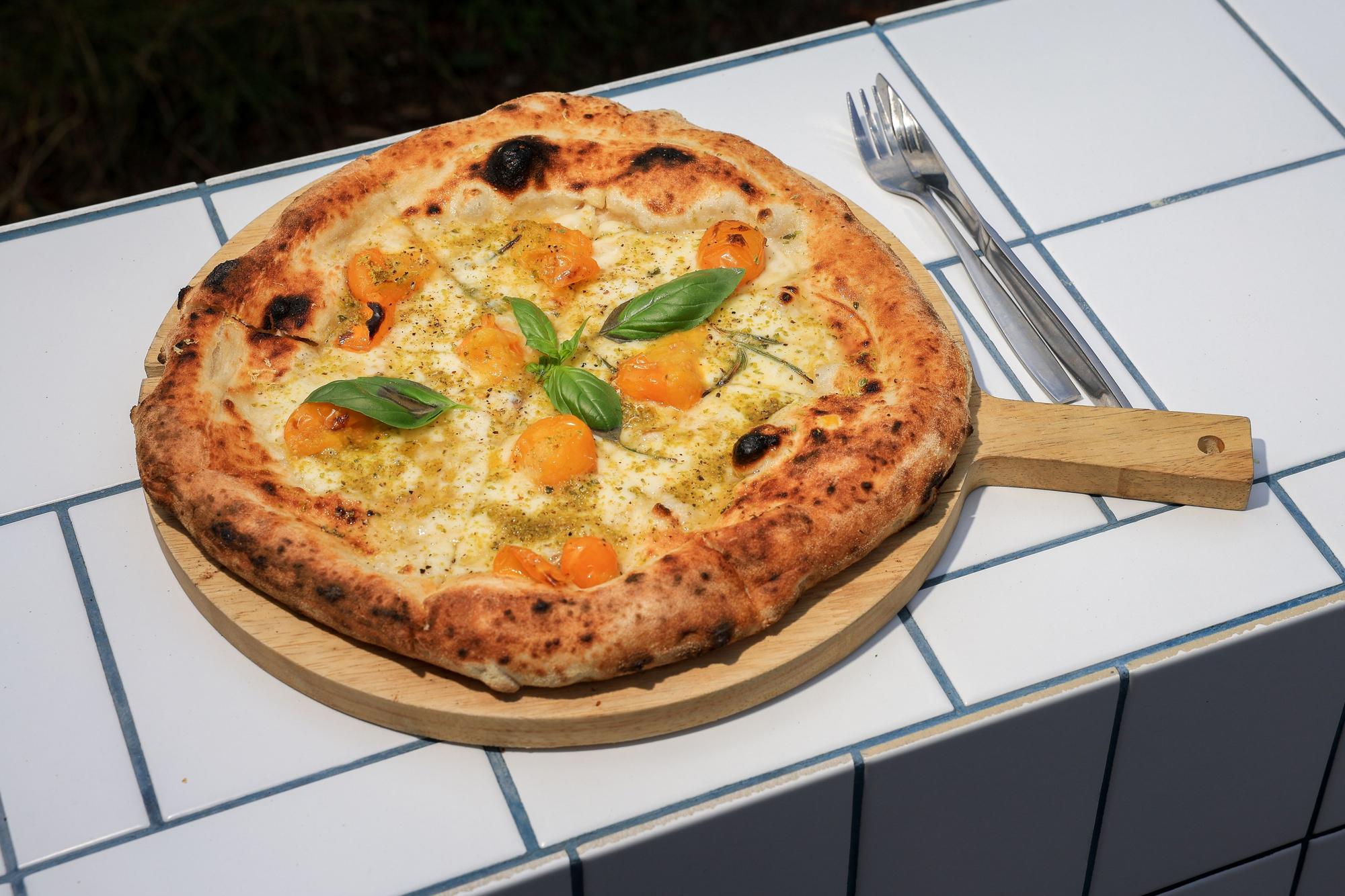 Eine Pizza ist auf einem Holzbrett zu sehen.