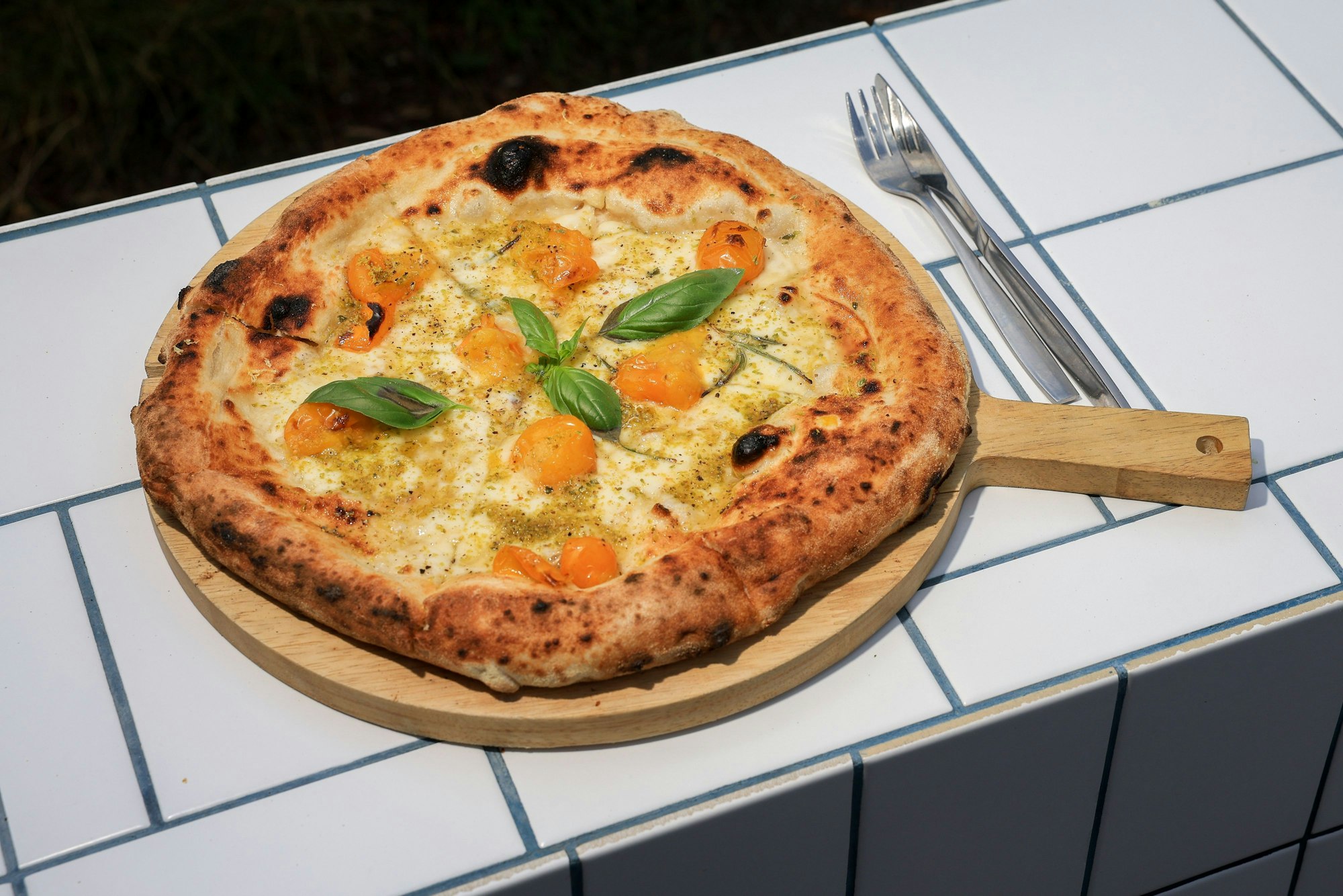 Eine Pizza ist auf einem Holzbrett zu sehen.