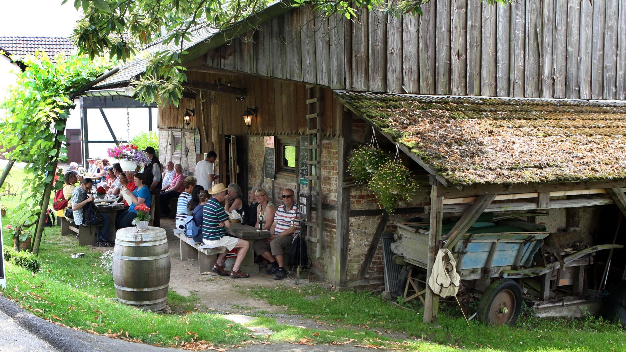 Menschen sitzen an Tischen vor der Krahmer Scheune in Nümbrecht-Krahm.