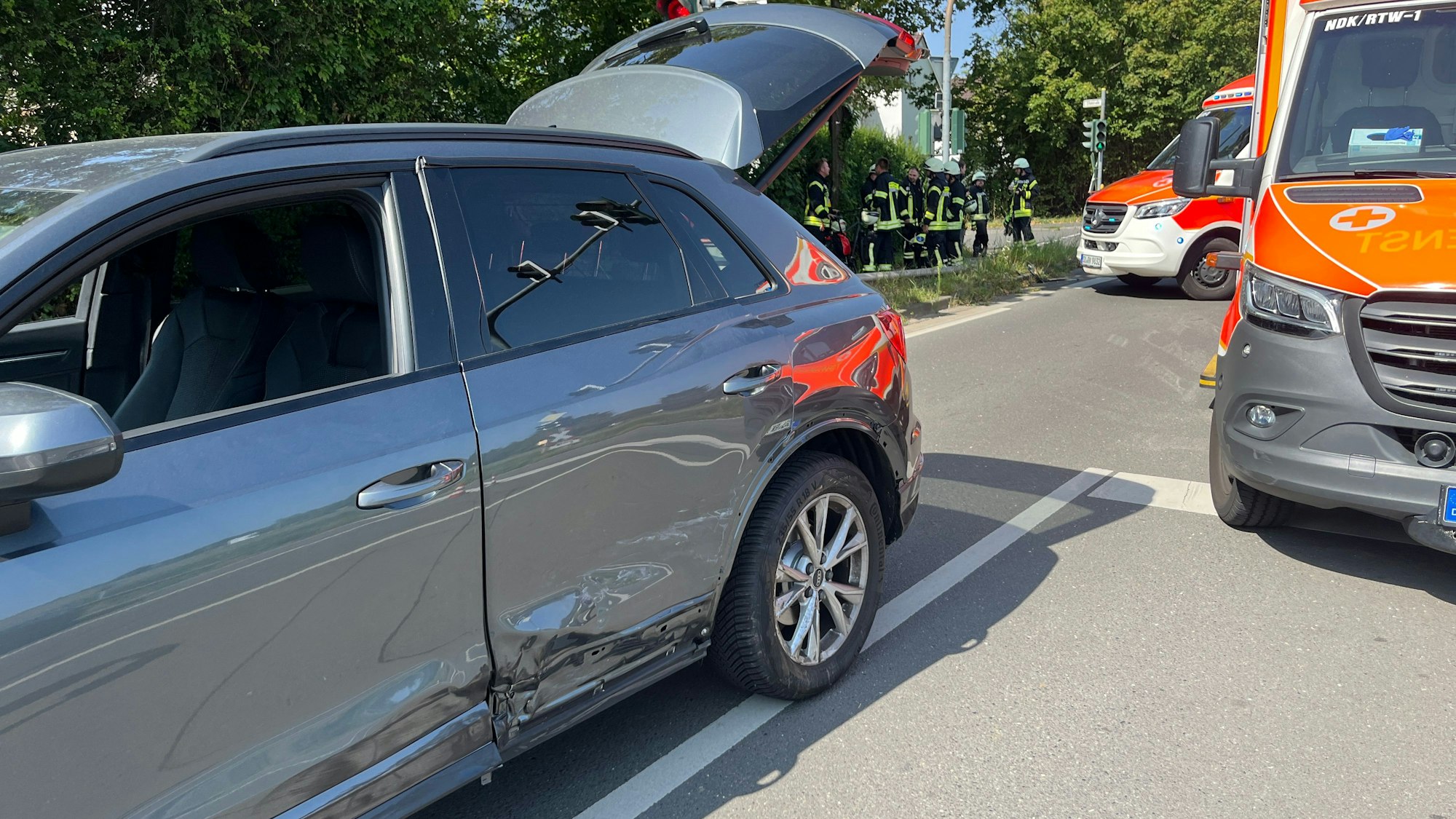 Zwei Rettungswagen stehen auf einer Straße, daneben ein beschädigtes Auto.