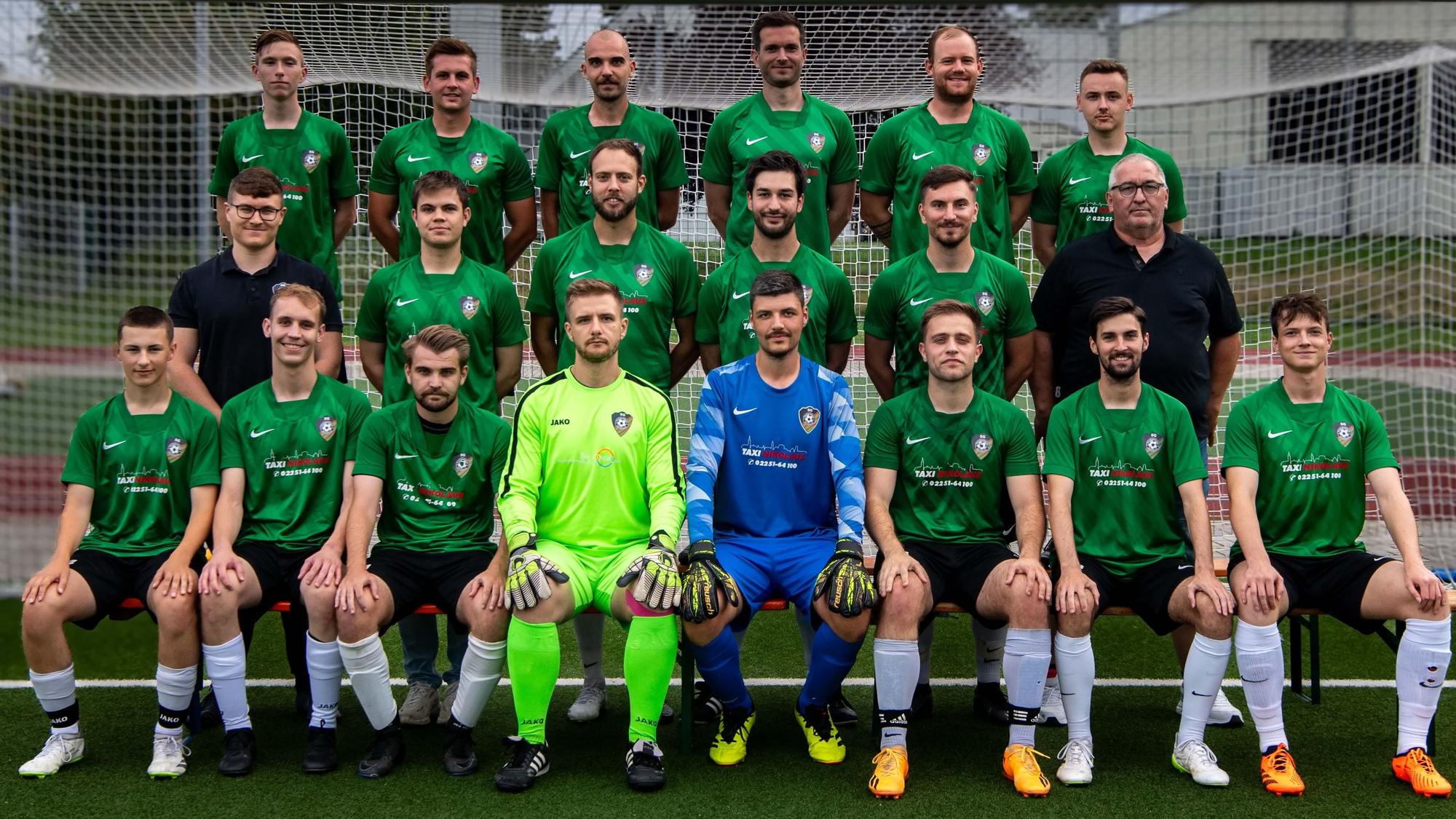 Beim Mannschaftsfoto sitzen und stehen die Herren des SG Flamersheim/Kirchheim vor einem Fußballtor.
