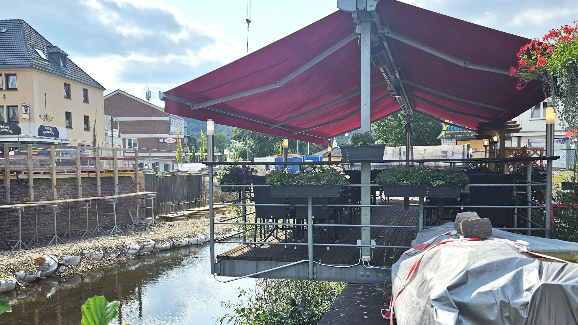 Das Bild zeigt die ganze Terrasse und den Teil, der über die Ufermauer der Olef hinausragt.