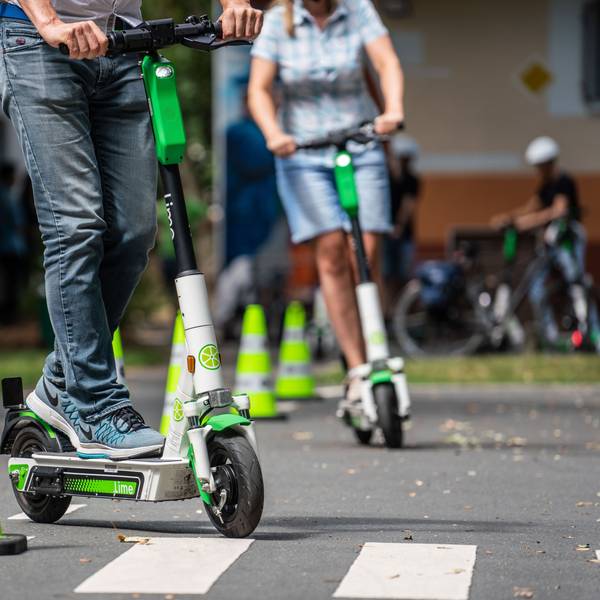 Teilnehmer an einem Fahrsicherheitstraining für Elektro-Tretroller fahren auf einem Verkehrsübungsplatz um die Pylonen (Symbolbild)