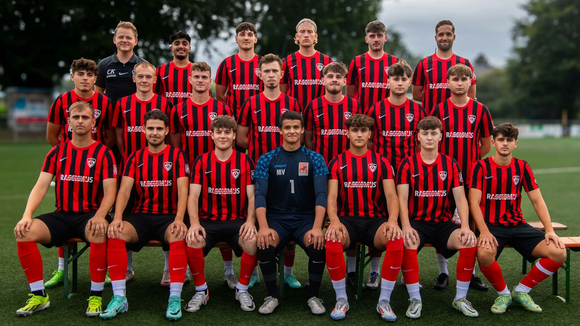 Die JSG Erft Euskirchen posiert auf einem Rasenplatz für ein Gruppenfoto. Im Hintergrund stehen Bäume.