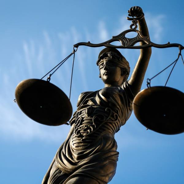 Eine Statue der Justitia hält eine Waage in der Hand.