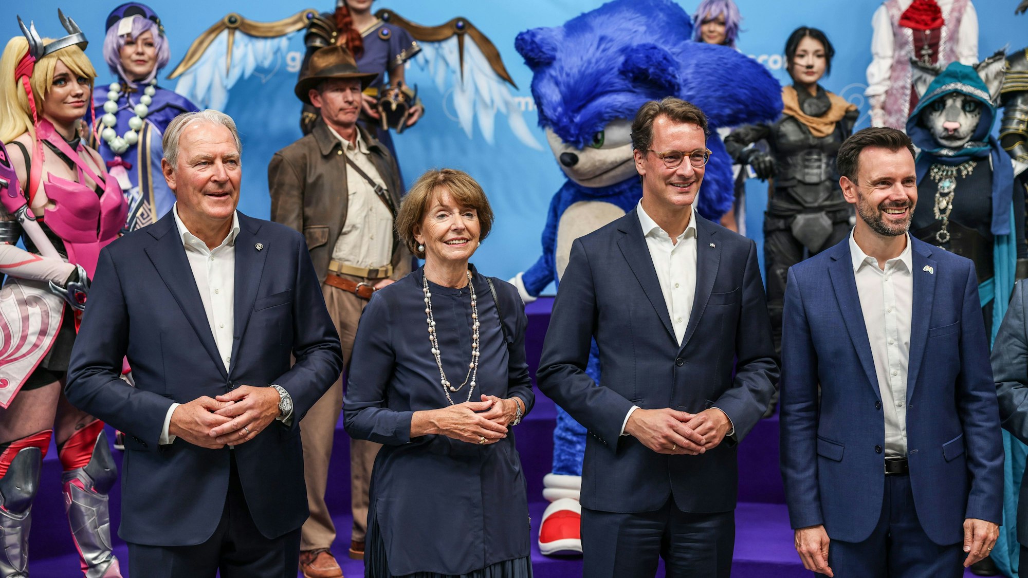 21.08.2024, Nordrhein-Westfalen, Köln: Hendrik Wüst (2.v.r., CDU), Ministerpräsident von Nordrhein-Westfalen, Gerald Boese (l), Vorstand der Kölnmesse, Henriette Reker (2.v.l. parteilos), Oberbürgermeisterin von Köln, und Felix Falk (r) , Geschäftsführer des Game-Verbandes, stehen vor der Eröffnung vor Cosplayern. Die Computer- und Videospielmesse Gamescom vom 21.-25.08.2024 in Köln statt. Foto: Oliver Berg/dpa +++ dpa-Bildfunk +++