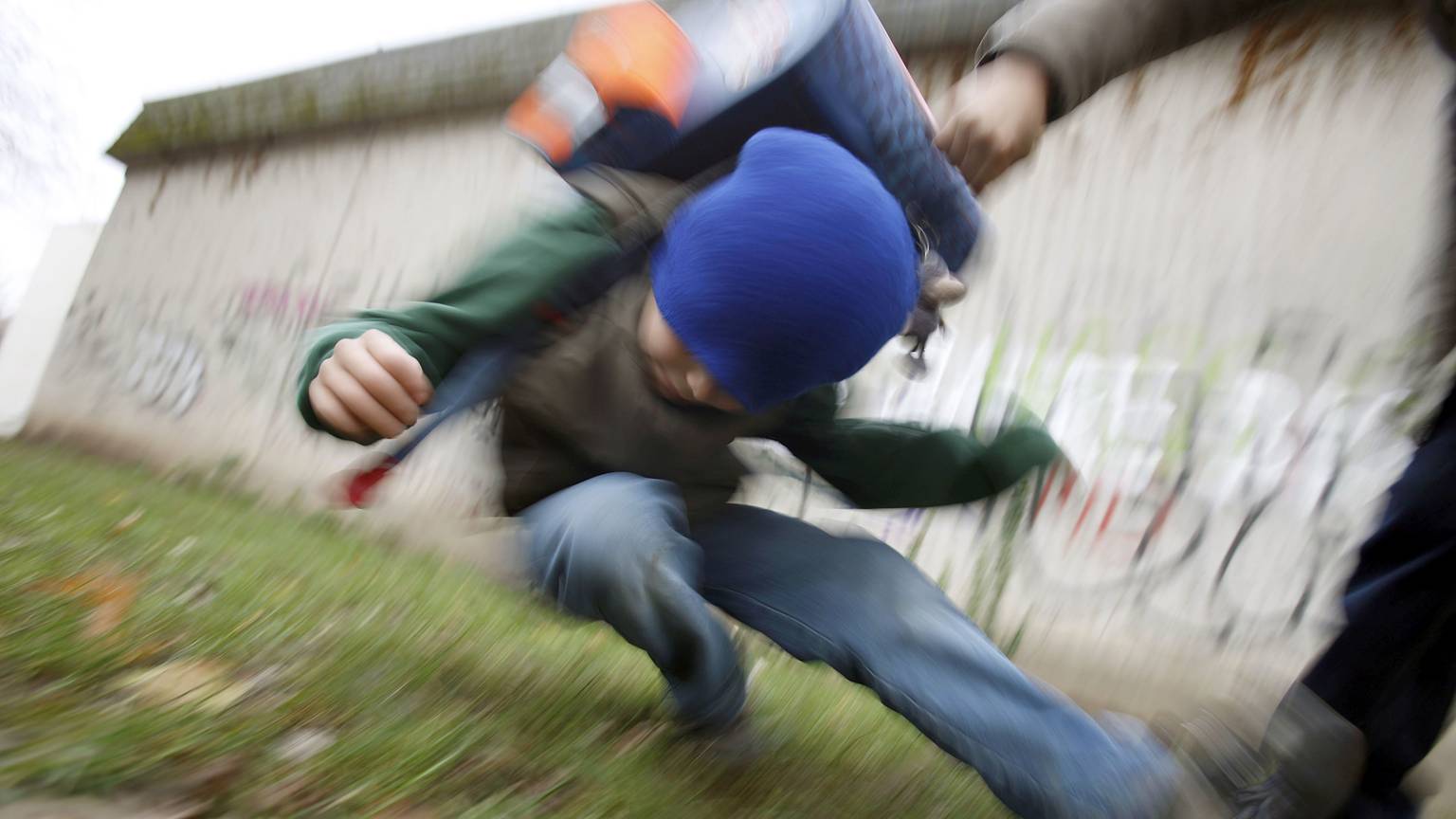 Ein Schüler drückt auf dem Schulhof eines Gymnasiums einen anderen Schüler zu Boden (gestelltes Illustrationsfoto).