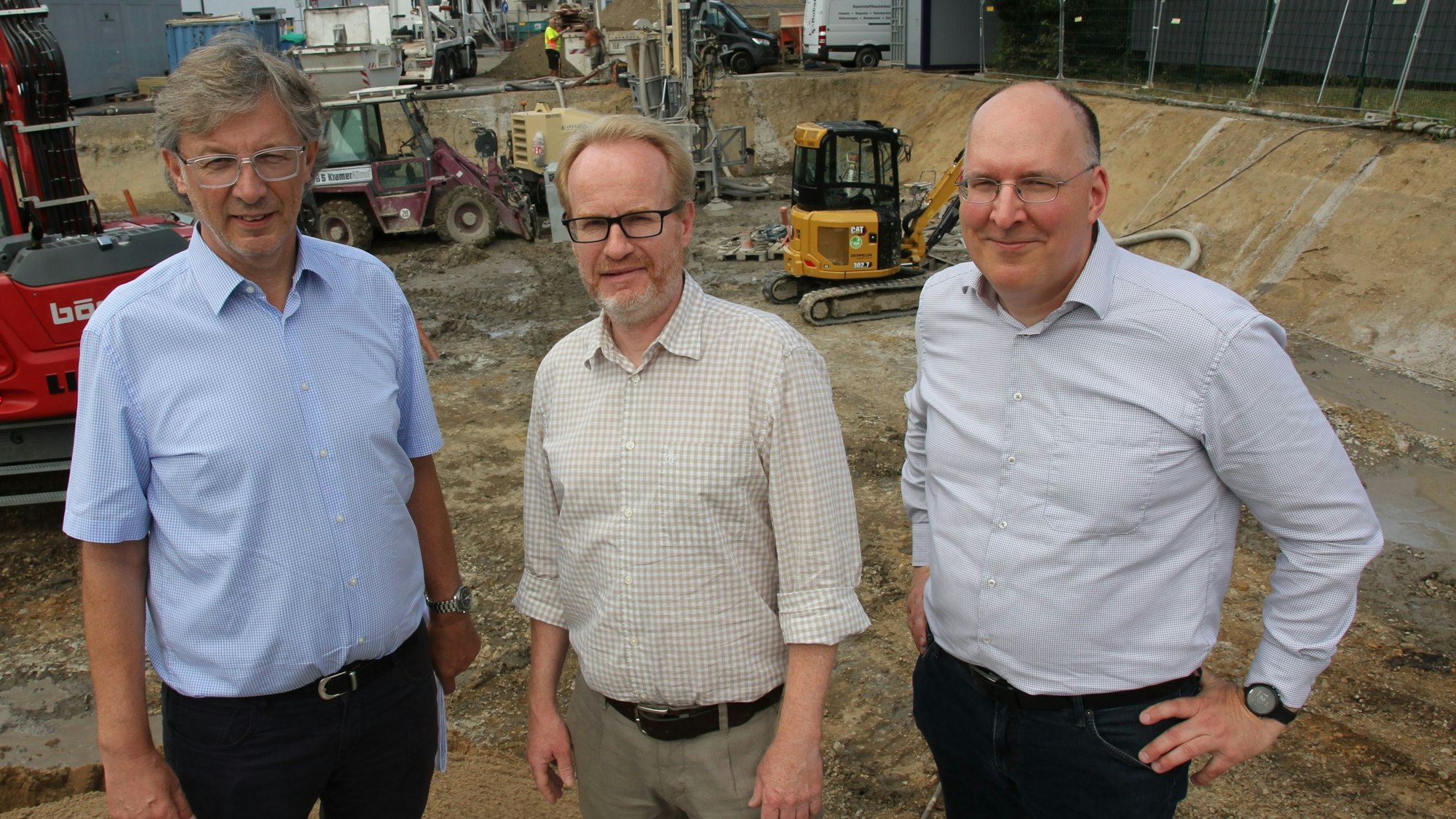 Drei Männer vor einer Baugrube