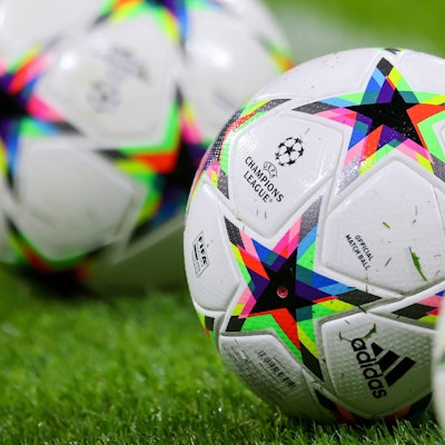 ußball mit dem Logo der Champions League liegen auf dem Rasen.