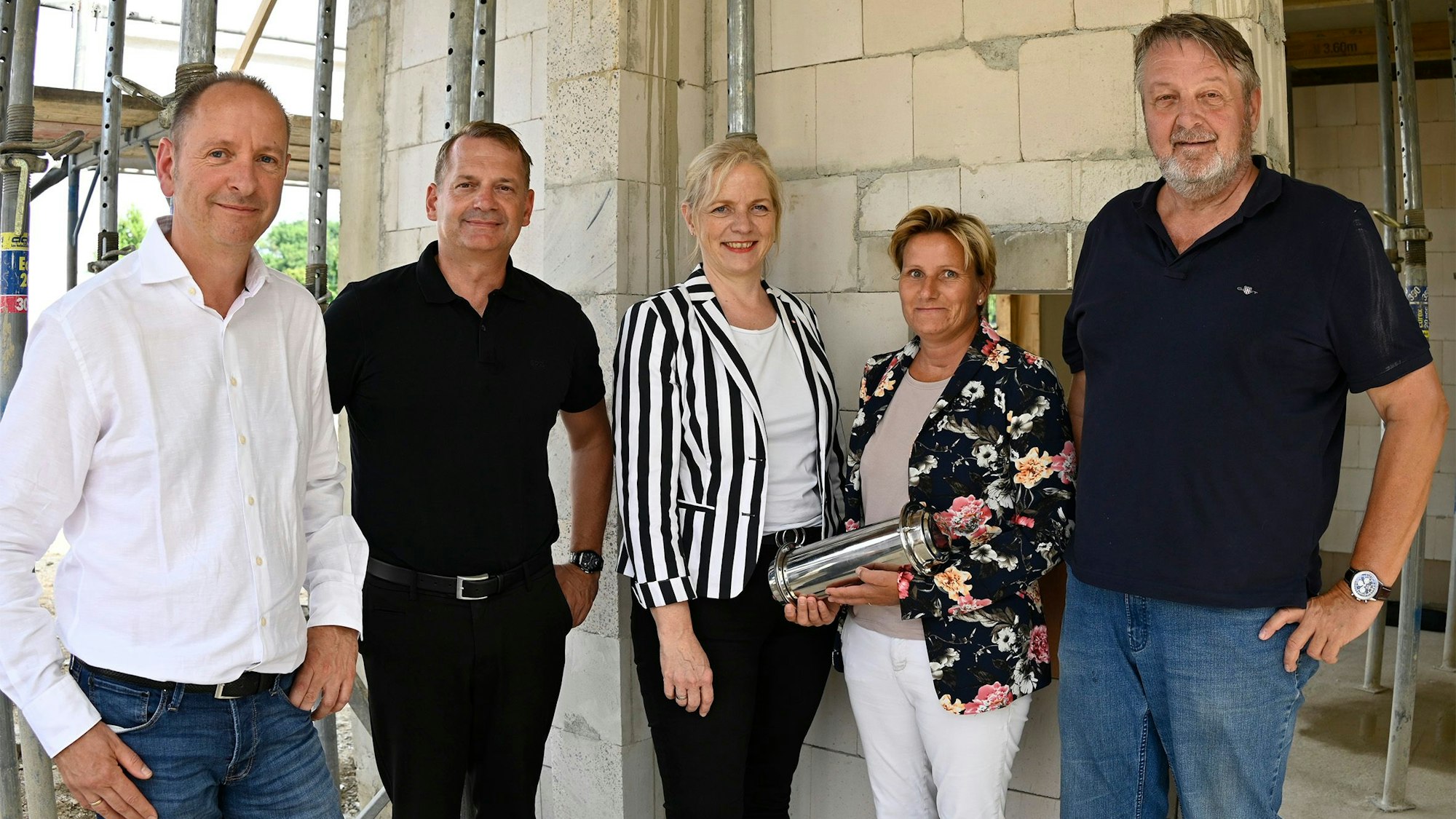 Männer und Frauen stehen in einem Rohbau.