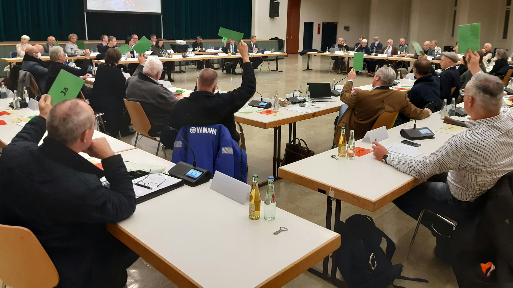 Abstimmung über den Haushalt im Rat (hier der Stadt Wiehl). Die Mitglieder halten grüne Karten in die Höhe.