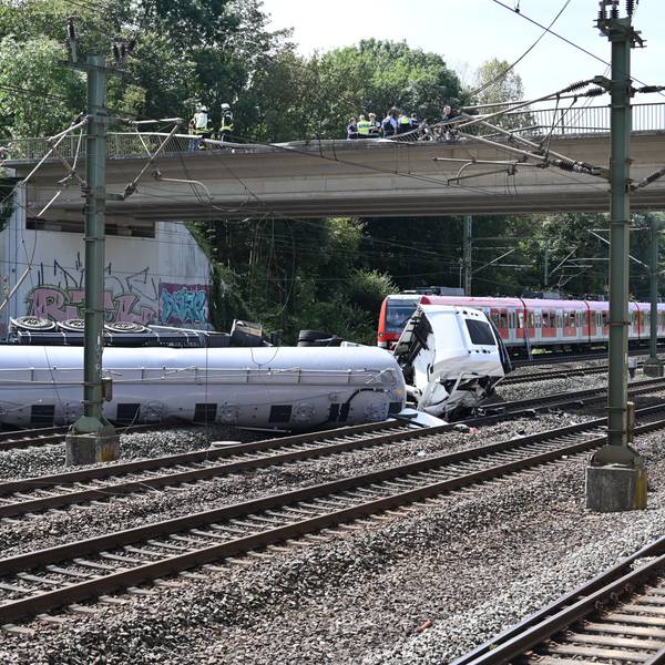 Das Bild zeigt einen Lkw, der auf den Gleisen liegt.