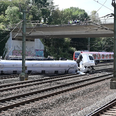 Das Bild zeigt einen Lkw, der auf den Gleisen liegt.
