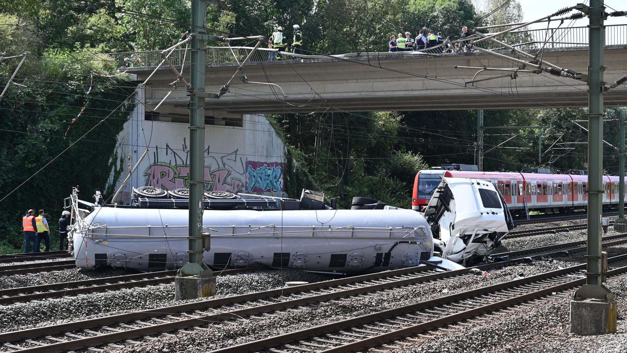 Das Bild zeigt einen Lkw, der auf den Gleisen liegt.