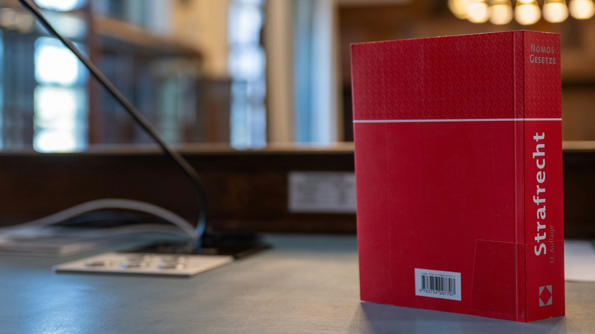 Das Gesetzbuch "Strafrecht" steht auf einem Tisch in einem Verhandlungssaal.