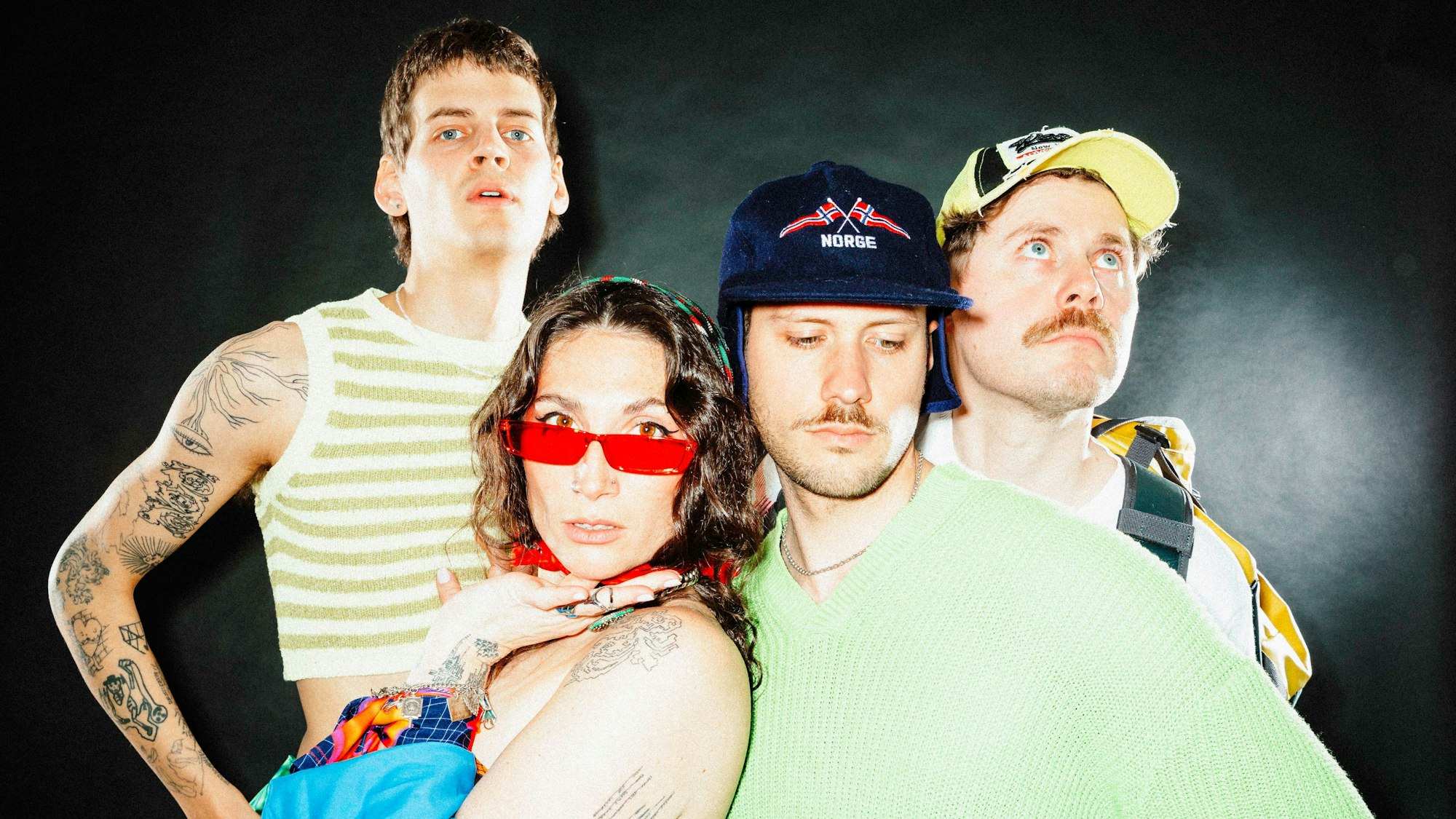 Drei Männer und eine Frau schauen in die Kamera.