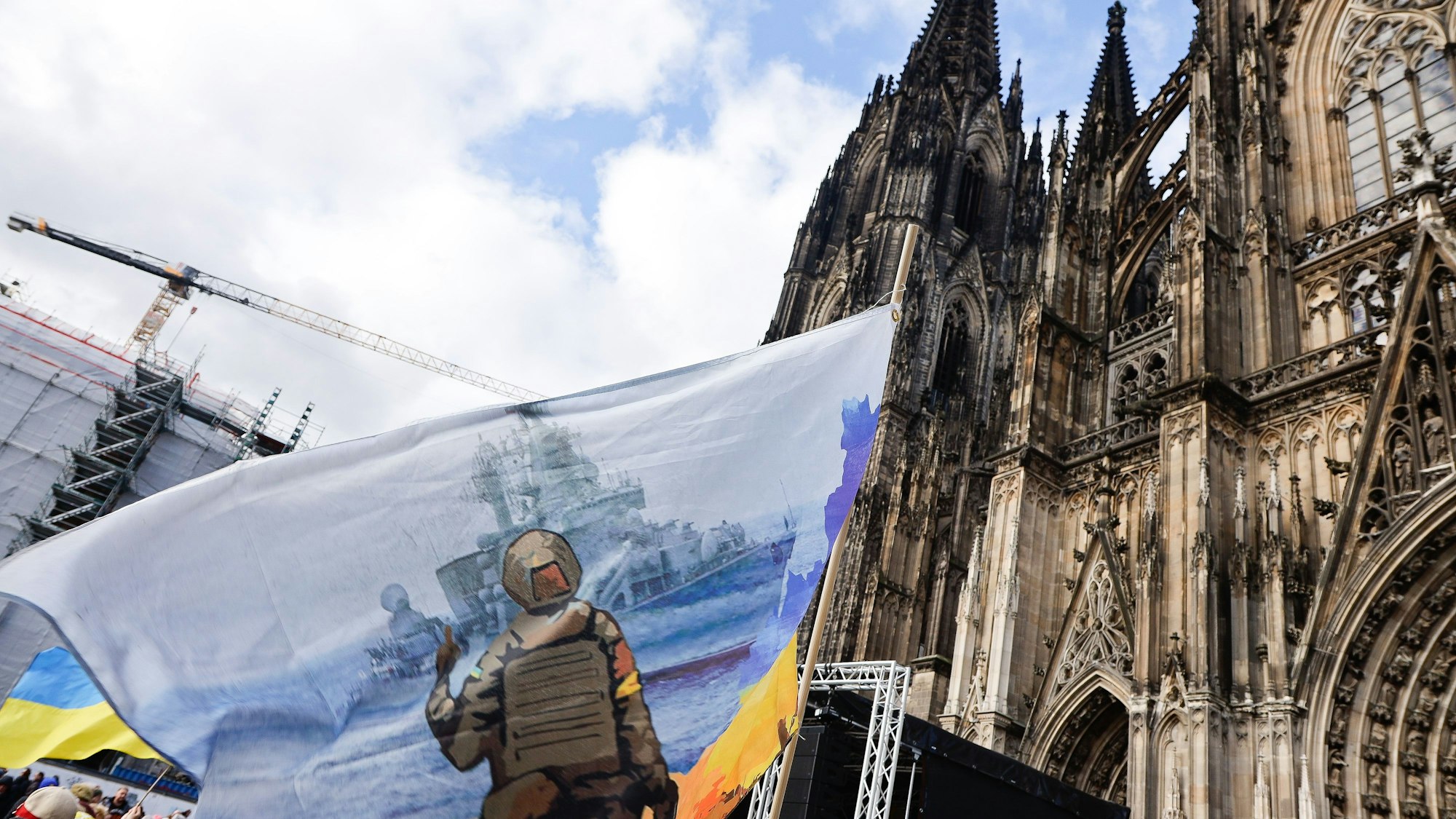 Eine ukrainische Fahne weht vor dem Kölner Dom im Wind.