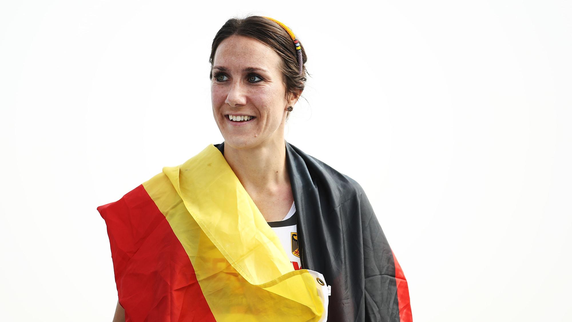 Irmgard Bensusan lächelt und hat eine Deutschlandflagge um ihre Schultern hängen.