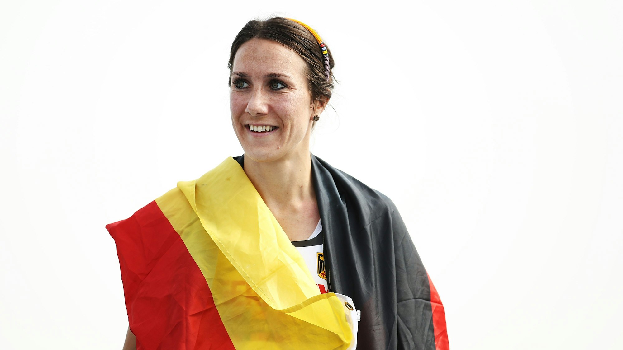 Irmgard Bensusan lächelt und hat eine Deutschlandflagge um ihre Schultern hängen.