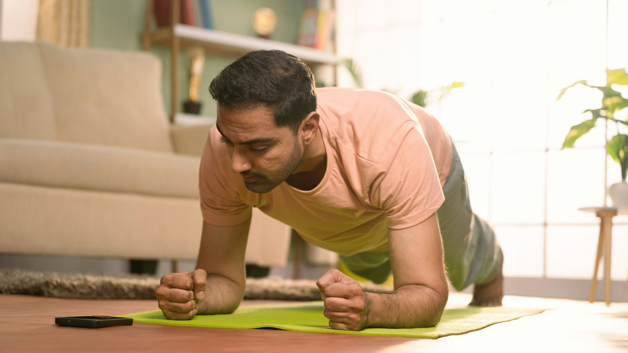 Ein Mann macht im Wohnzimmer auf einer Sportmatte eine Plank