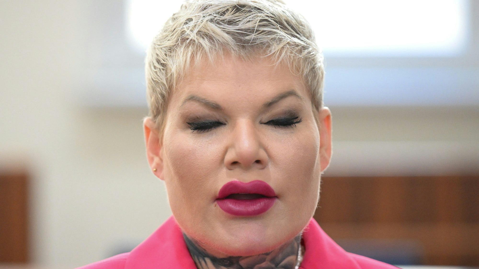 Schlagersängerin Melanie Müller sitzt mit pinker Jacke im Gerichtssaal.