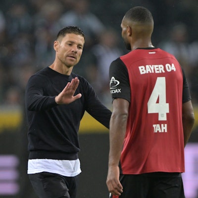 Trainer Xabi Alonso von Bayer Leverkusen schlägt nach dem Spiel mit Spieler Jonathan Tah ein.