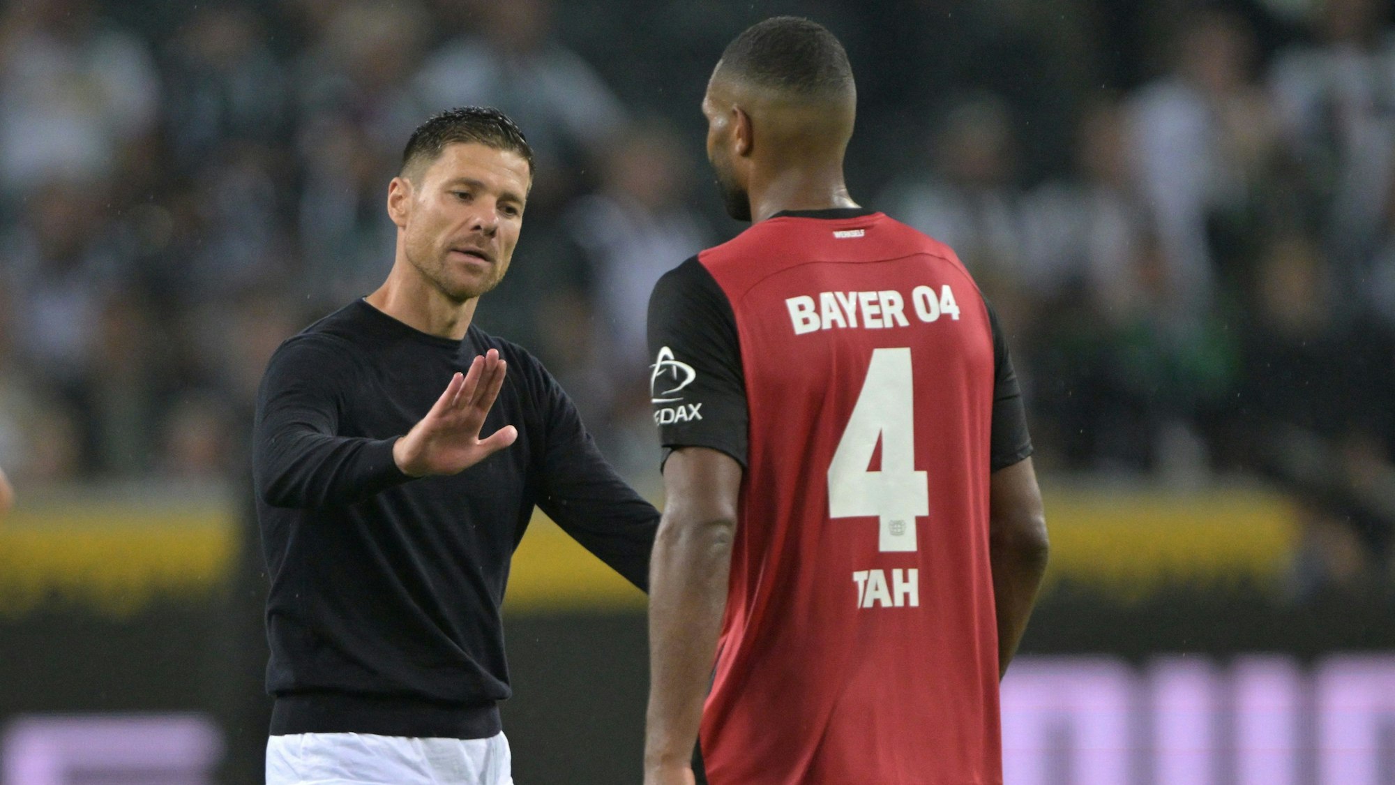 Trainer Xabi Alonso von Bayer Leverkusen schlägt nach dem Spiel mit Spieler Jonathan Tah ein.