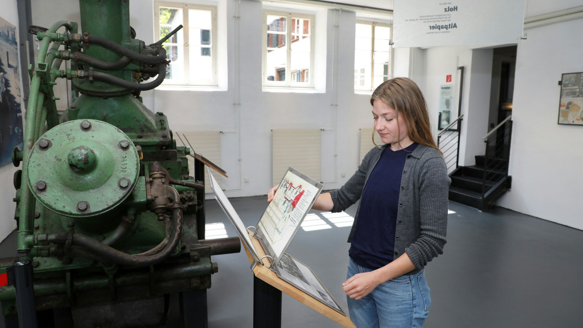 Eine Frau blättert in Infotafeln in einem Museumsraum der Papiermühle alte Dombach.